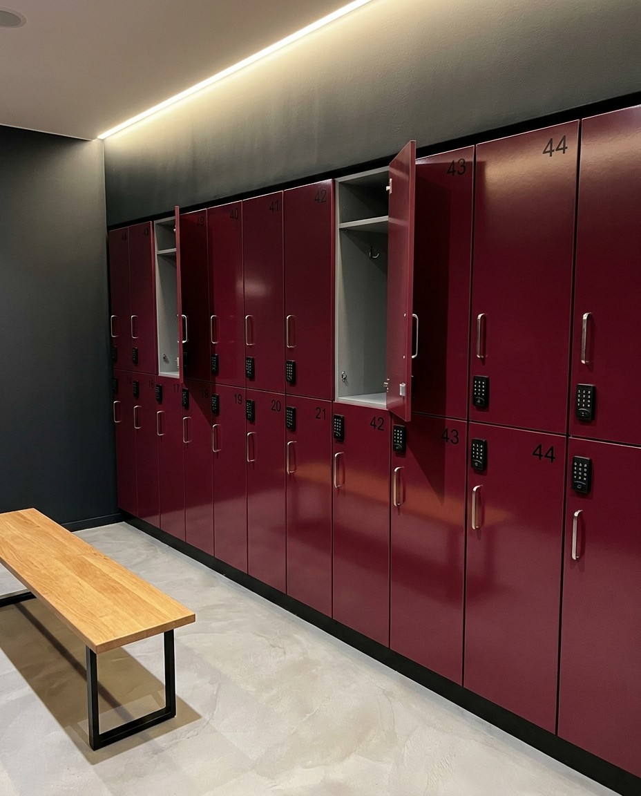 Gym changing room by Kavela: burgundy gloss lockers with keypad locks and an oak bench
